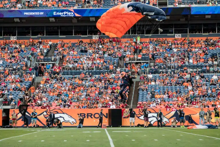 Broncos offense struggles: a parachutist lands on the field before a Denver Broncos game at Mile High