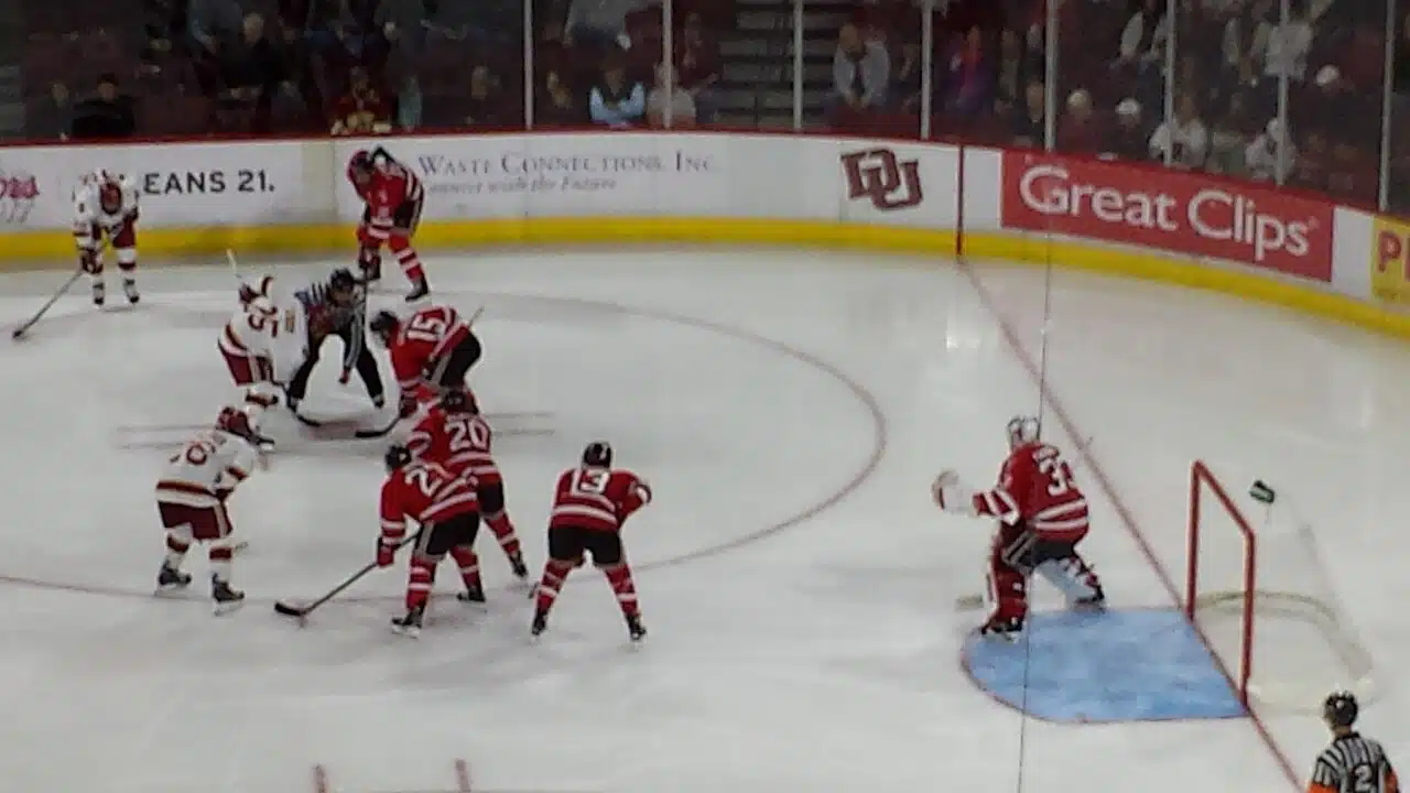 University of Denver hockey players in white face off against RPI at Magness Arena